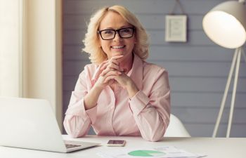 A happy mature businesswoman wearing a blonde wig.