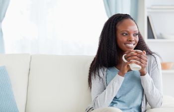 Afro-American woman with long hair holding a cup of coffee.