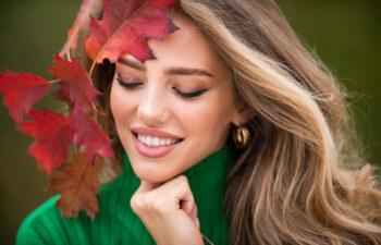 Beauty woman holds autumn red leaf