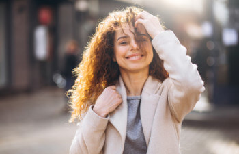 A woman with curly hair wearing a light coat.