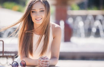 Young beautiful attractive woman with long straight hair sitting at a table in a city cafe.