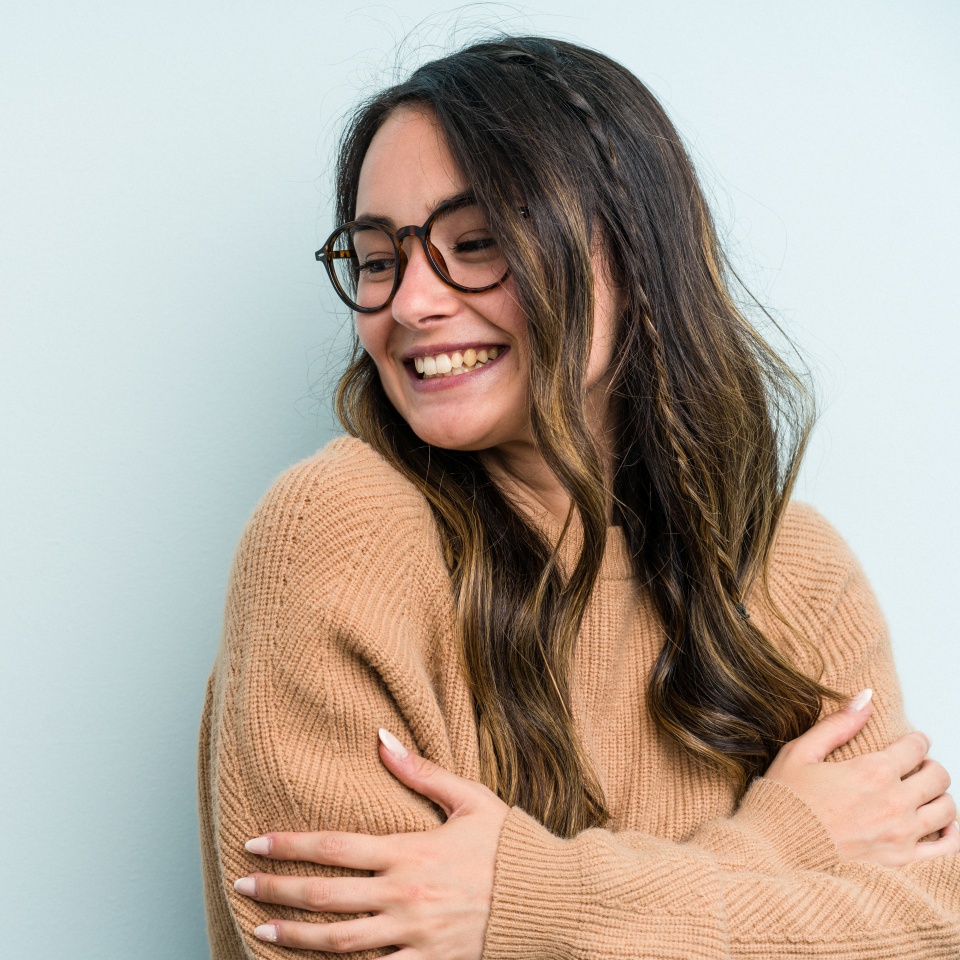Young caucasian woman isolated on blue background smiling confident with crossed arms.