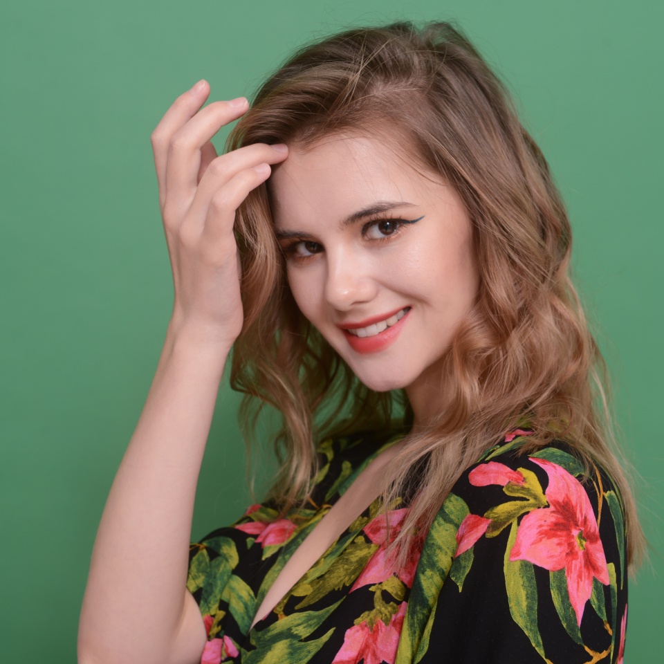 Portrait of beautiful young woman with makeup and gorgeous hair styling on green background