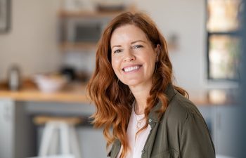 Woman with red hair smiling in a kitchen setting
