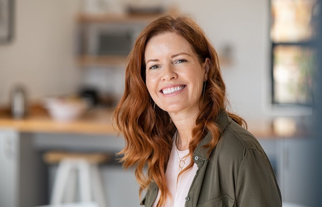 Woman with red hair smiling in a kitchen setting