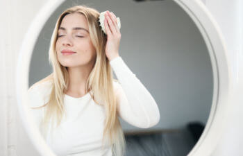Blond woman doing self hair scalp massage with massager at home