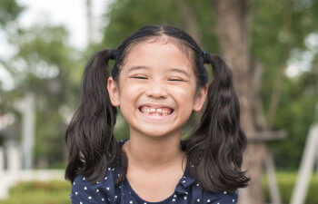 Close-up of a smiling Asian girl with pigtails.