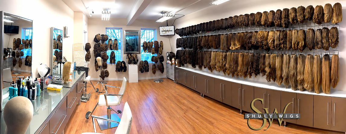 A wall display featuring numerous wigs in various shades of brown and blonde, arranged neatly on hooks above a row of cabinets.