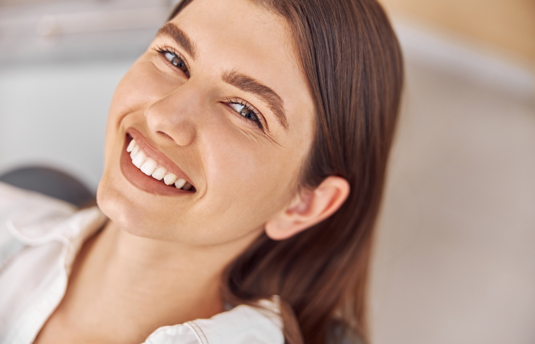 Attractive woman visiting dental clinic. Happy young woman sitting in dental chair at dentist office